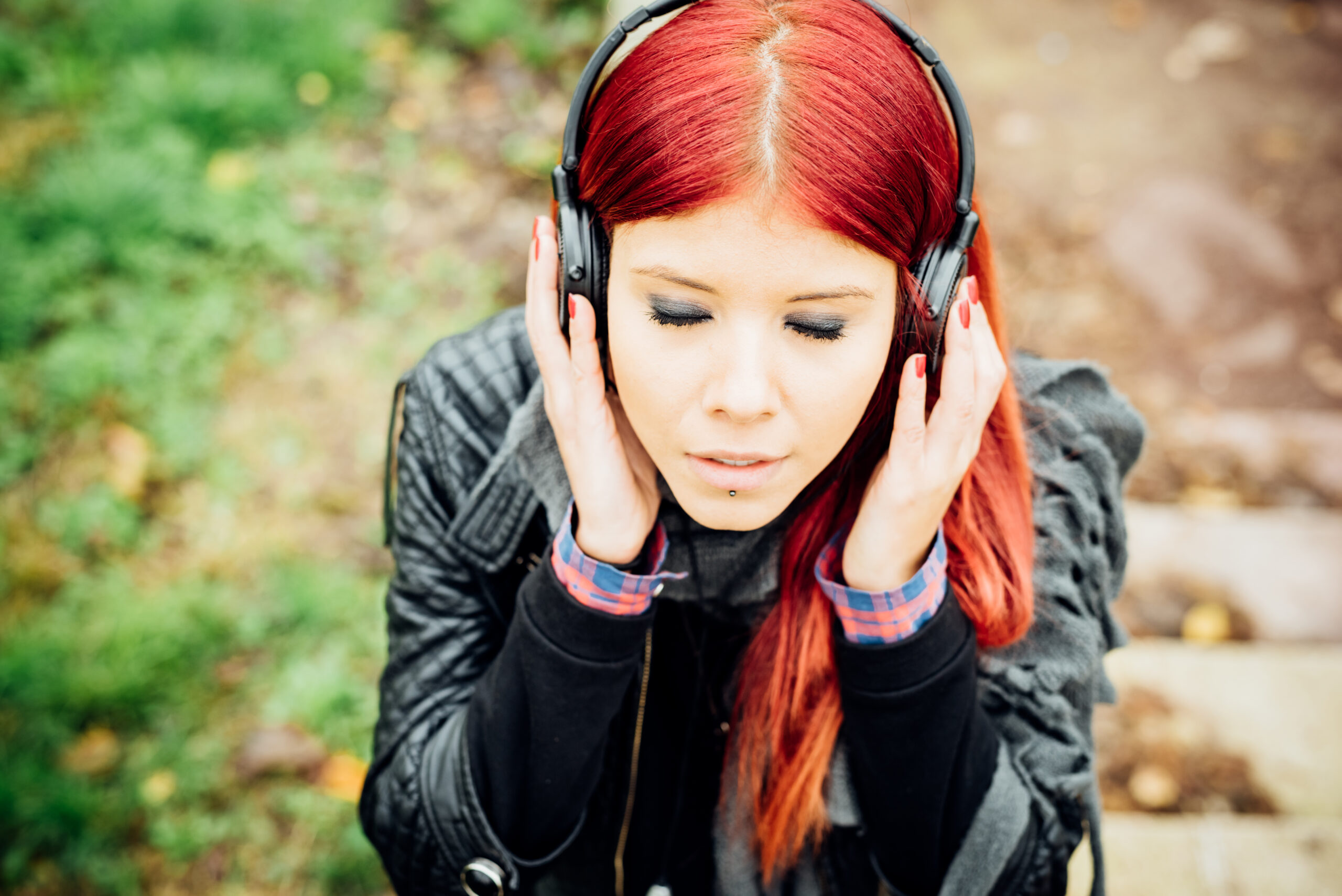 Portrait of young beautiful red hair venezuelan woman outdoor  listening music with headphones and eyes closed - relaxing, music, technology concept